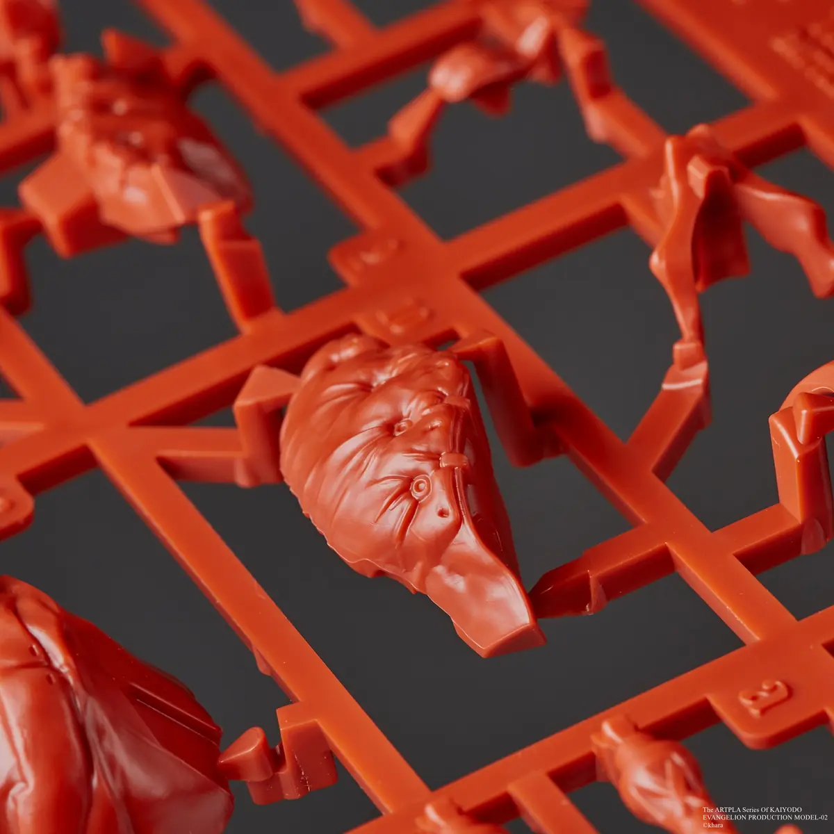 Close-up of a sculpted face component attached to a red plastic runner