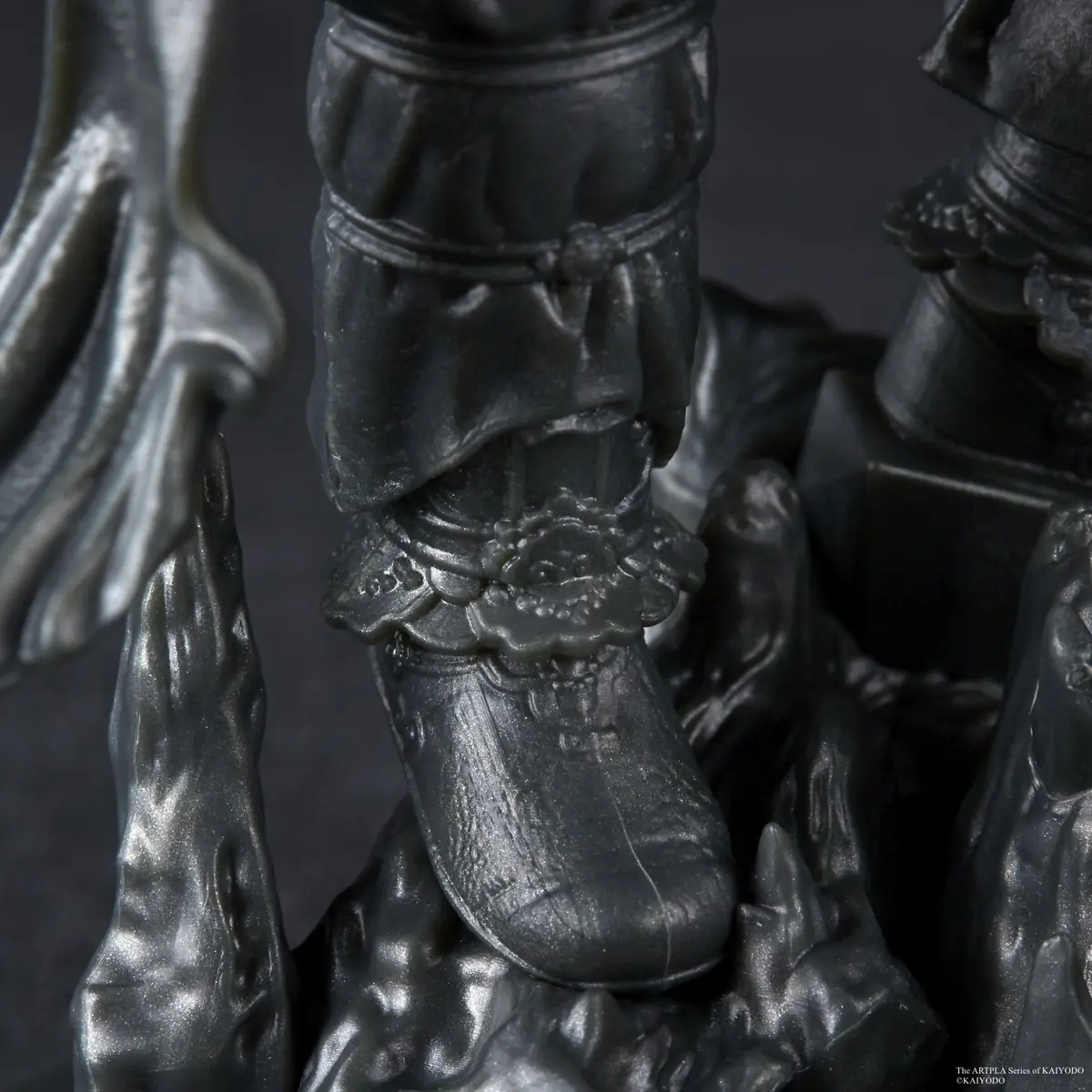 Macro view of an assembled gray model's armored boot and rocky sculpted base