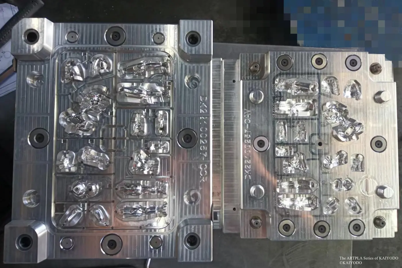 Open metal mold with additional sculpted figure-component cavities photographed from above