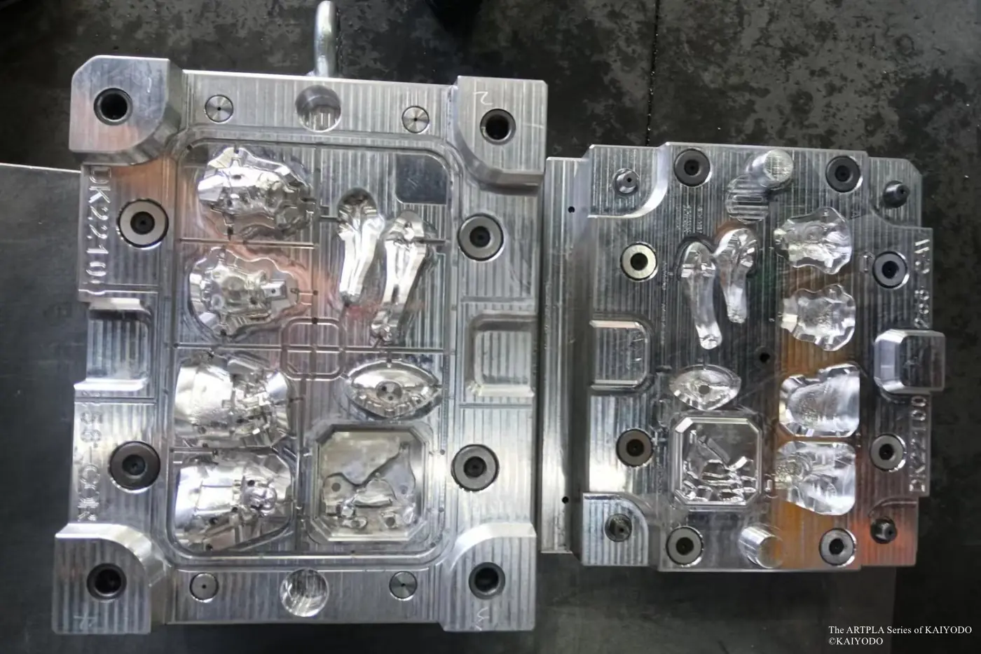 Open metal mold with several larger sculpted component cavities photographed from above