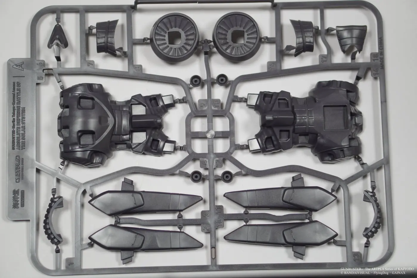 Dark gray plastic runner with large angular shells, circular details and pointed armor components