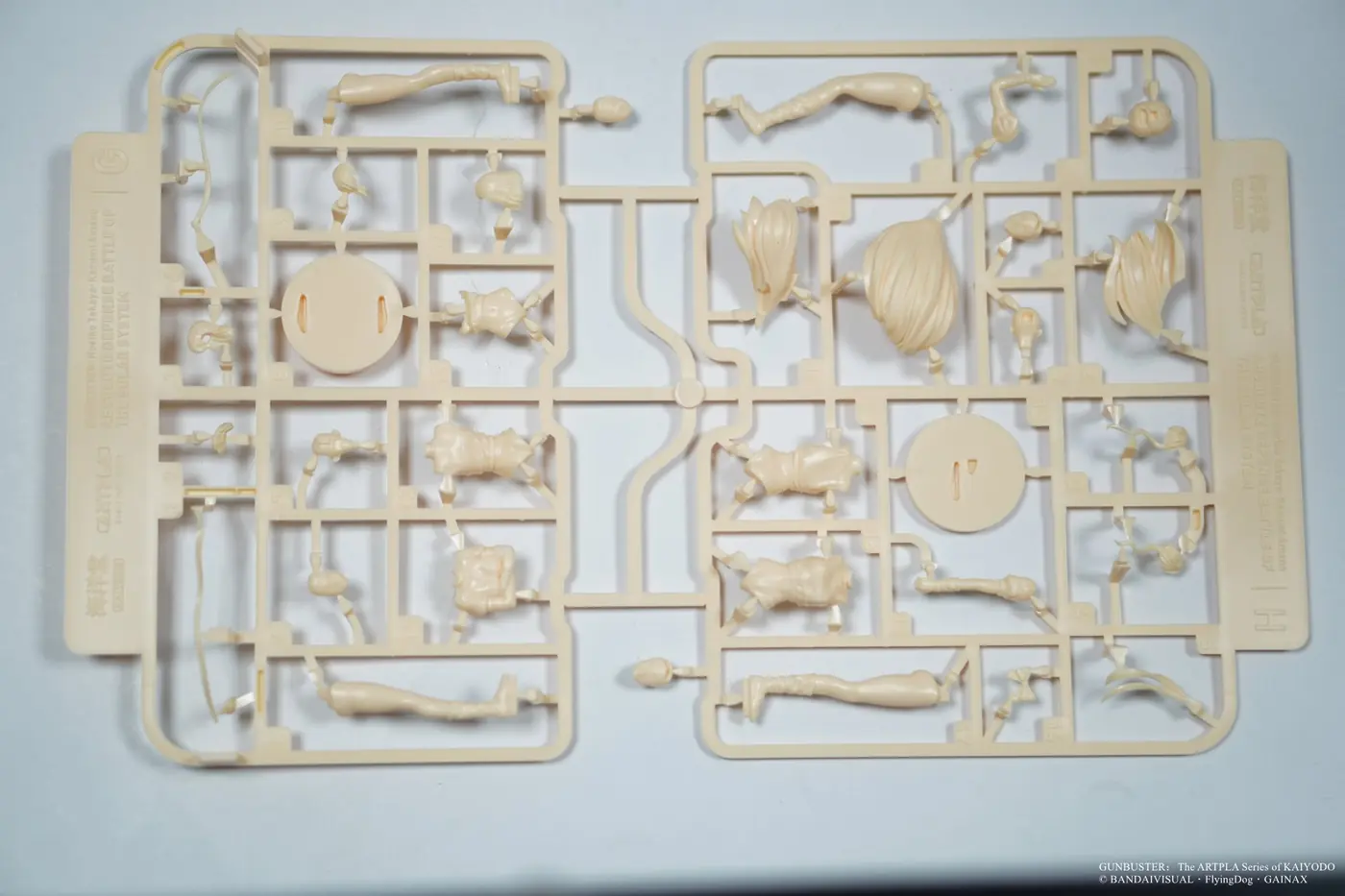 Pale-orange plastic runners containing character body, hair and round base parts