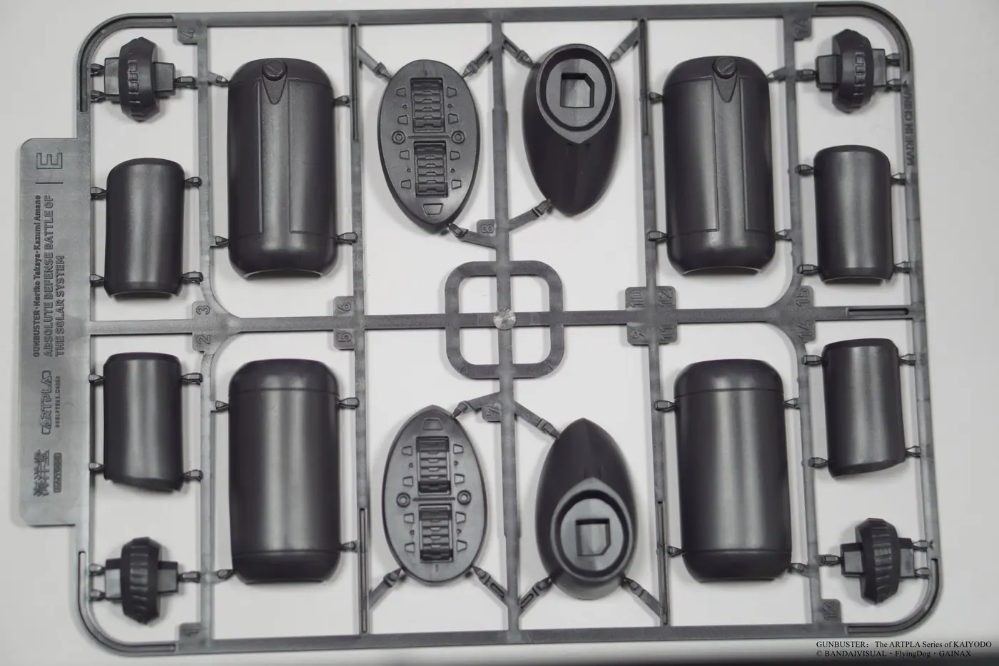Dark gray plastic runner with paired large cylinders, smaller cylinders, oval panels and connectors