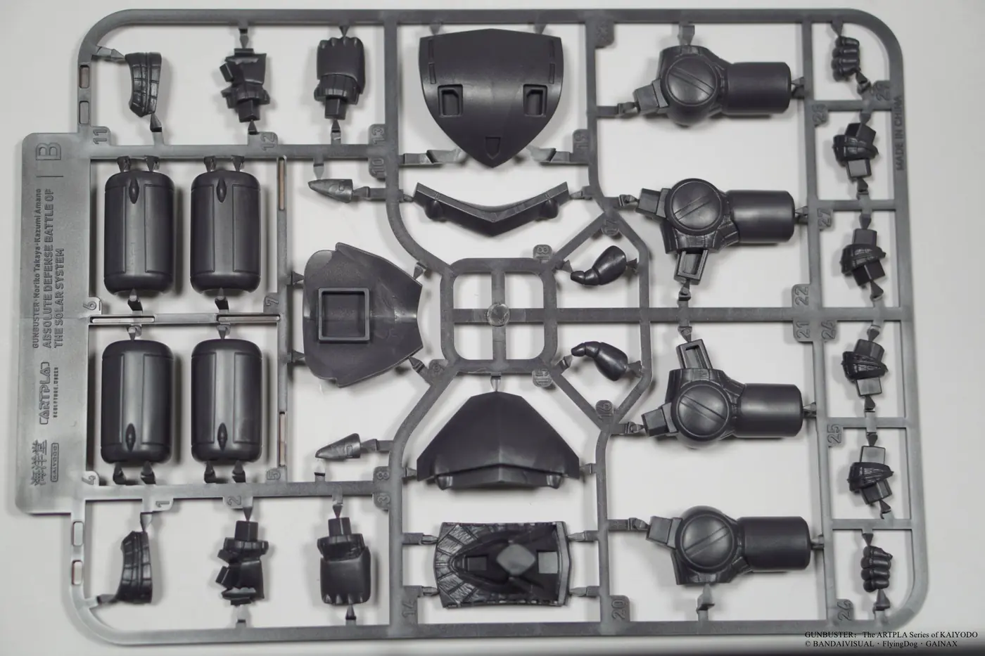 Dark gray plastic runner with cylindrical shells, angular panels, hands and small mechanical parts