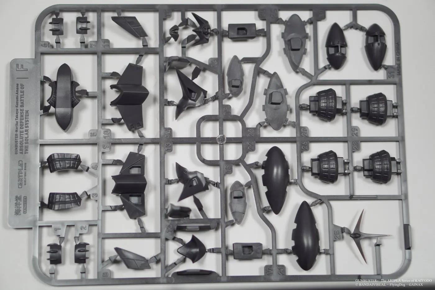 Dark gray plastic runner with assorted curved, angular and mechanical model parts