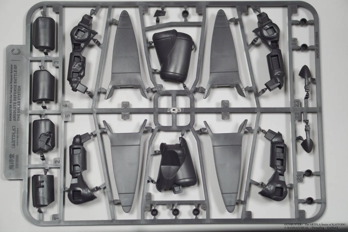 Dark gray plastic runner with long tapered panels, cylindrical pieces and small joint components
