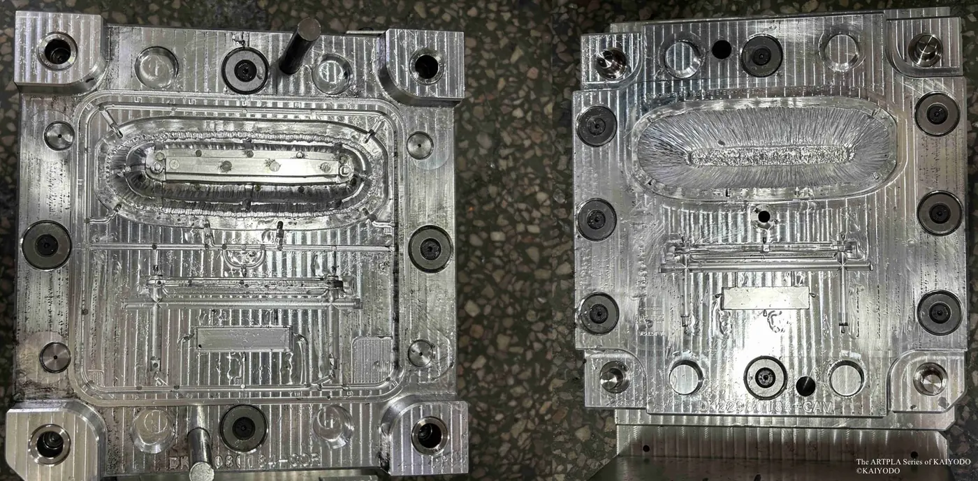 Two metal tooling plates with long oval cavities and fine runner channels